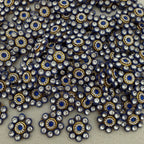 Close-up of decorative embellishments with blue centers and gold and silver accents on a neutral background.