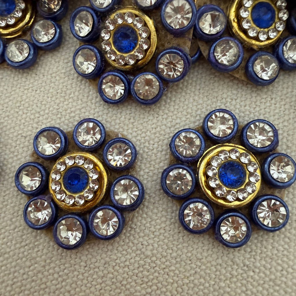 Close-up of decorative buttons with blue, gold, and crystal design on a textured surface.