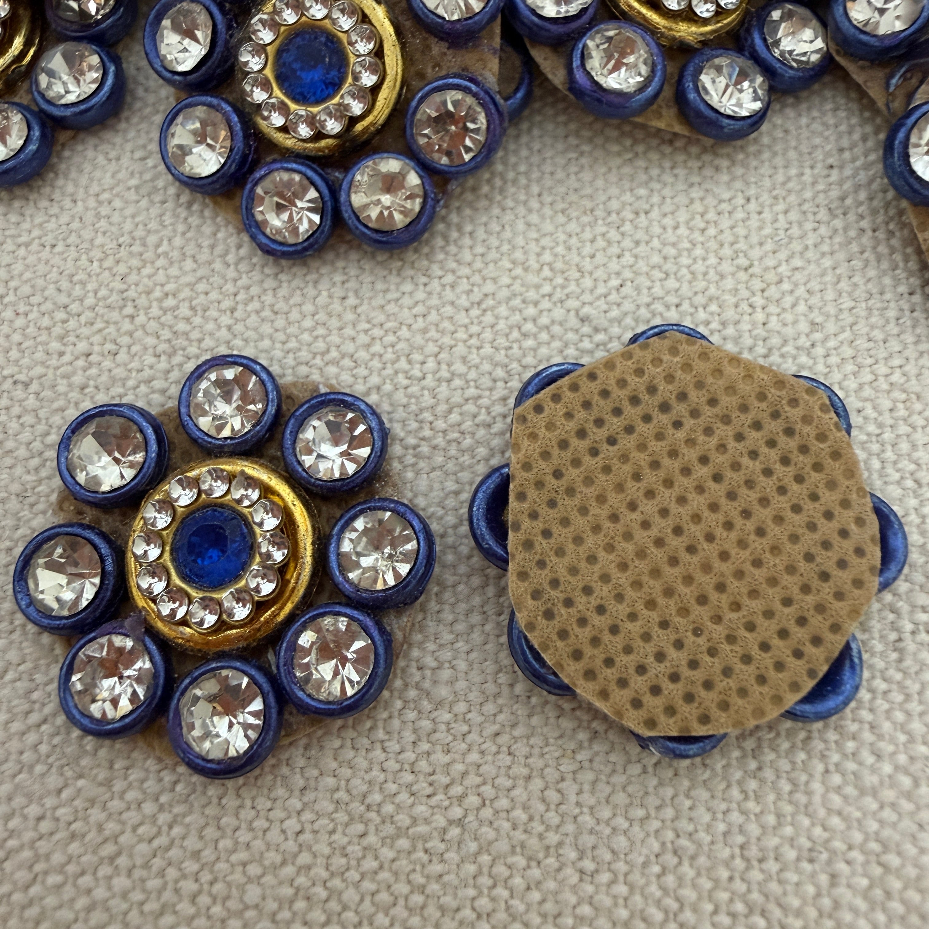 Decorative buttons with gemstones and a textured brown circle on a textured surface