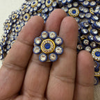 Close-up of a hand holding a decorative button with blue and gold accents.