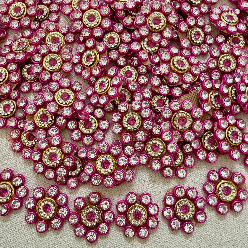 Close-up of pink and gold embellishments with clear stones on a textured surface