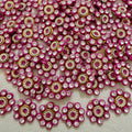 Close-up of pink and gold embellishments with clear stones on a textured surface