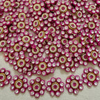 Close-up of pink and gold embellishments with clear stones on a textured surface