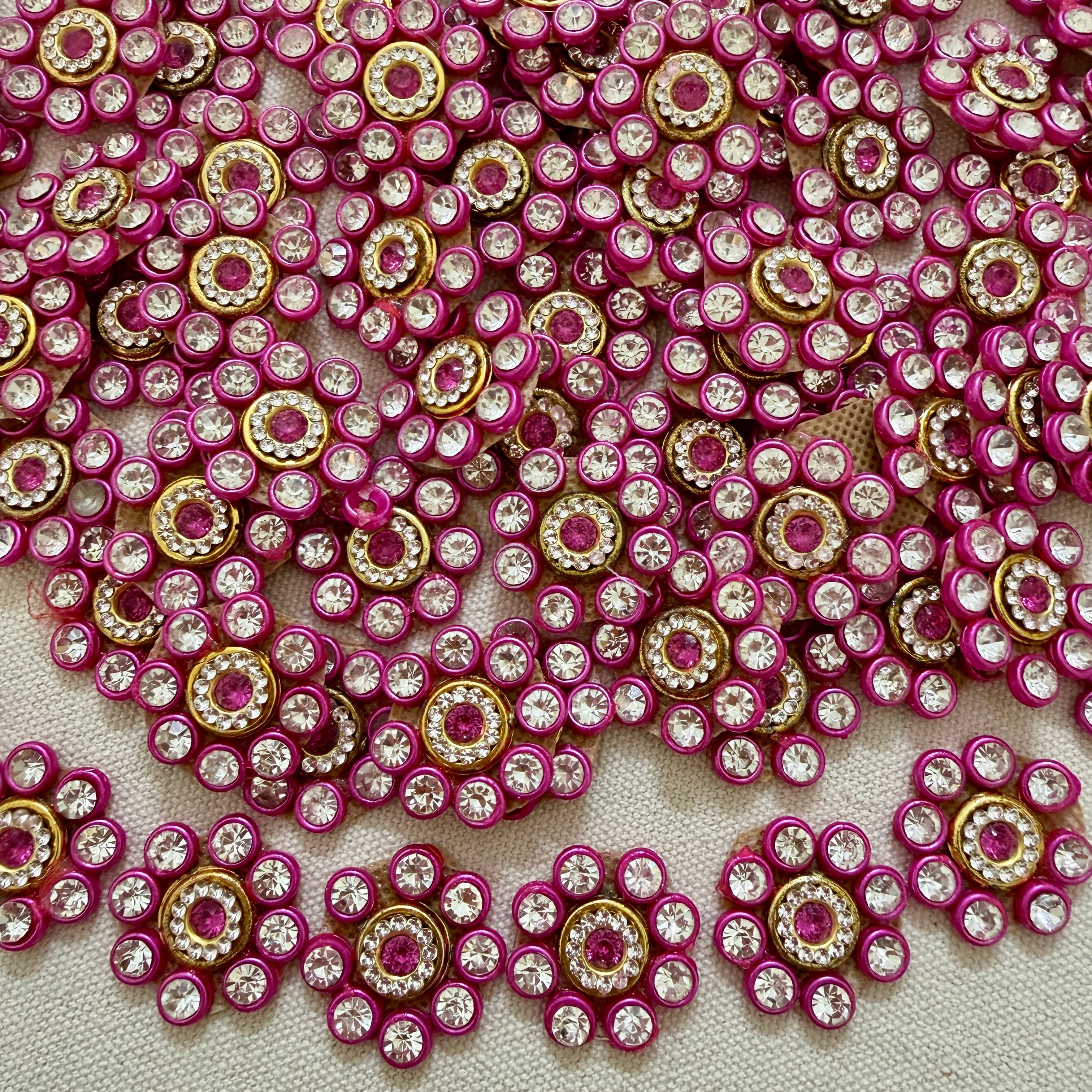 Close-up of pink and gold embellishments with clear stones on a textured surface