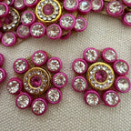 Decorative buttons with pink and gold design on a textured surface