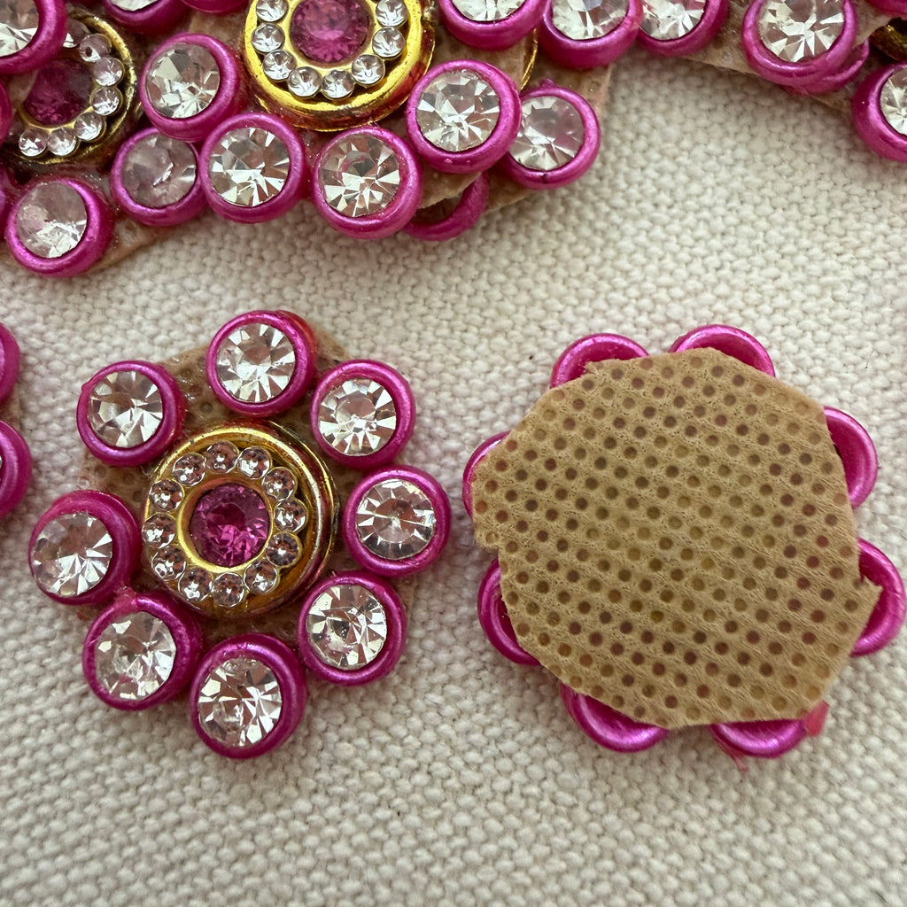 Decorative buttons with pink and gold embellishments on a textured surface