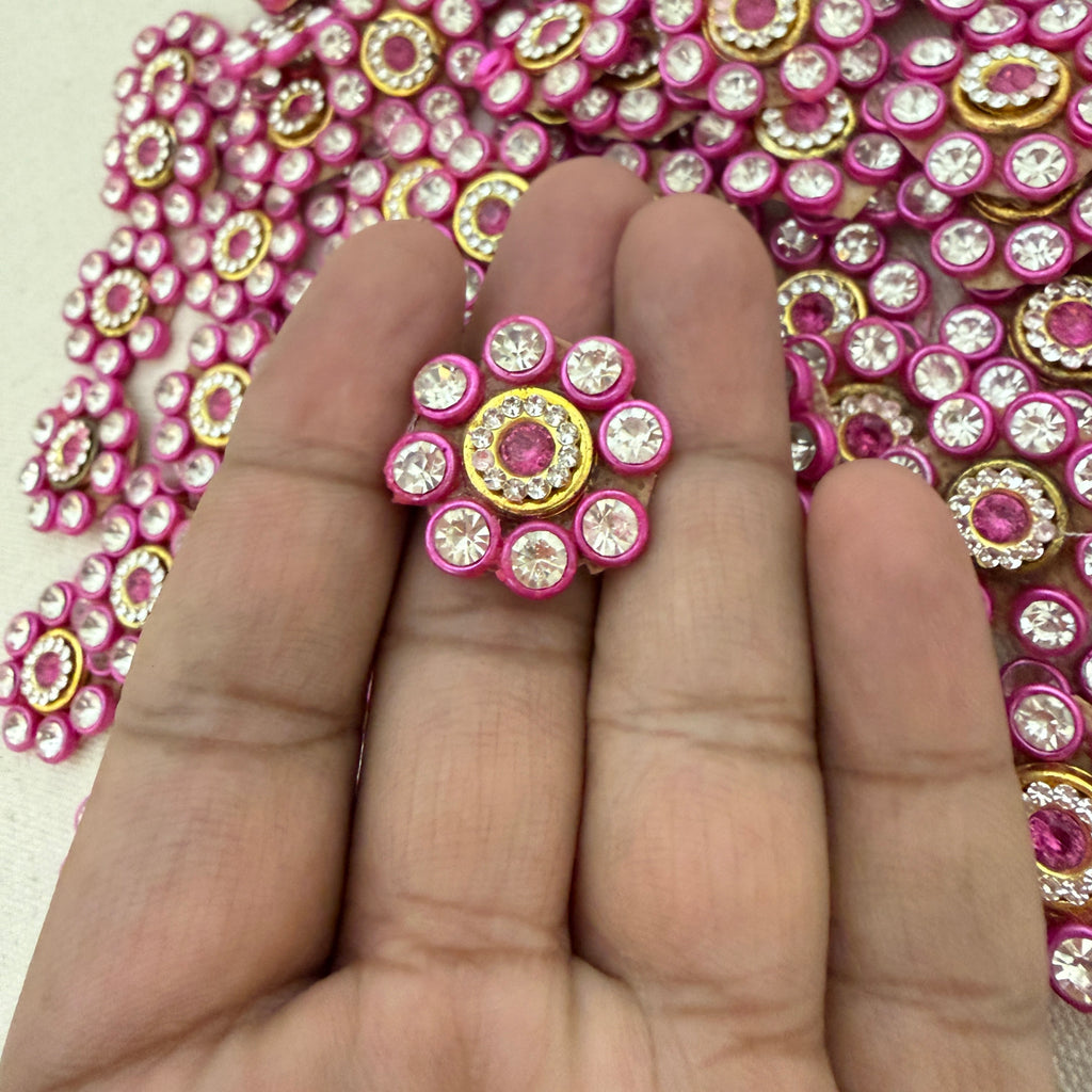 Decorative pink and gold embellishment on a hand with a pink rhinestone background