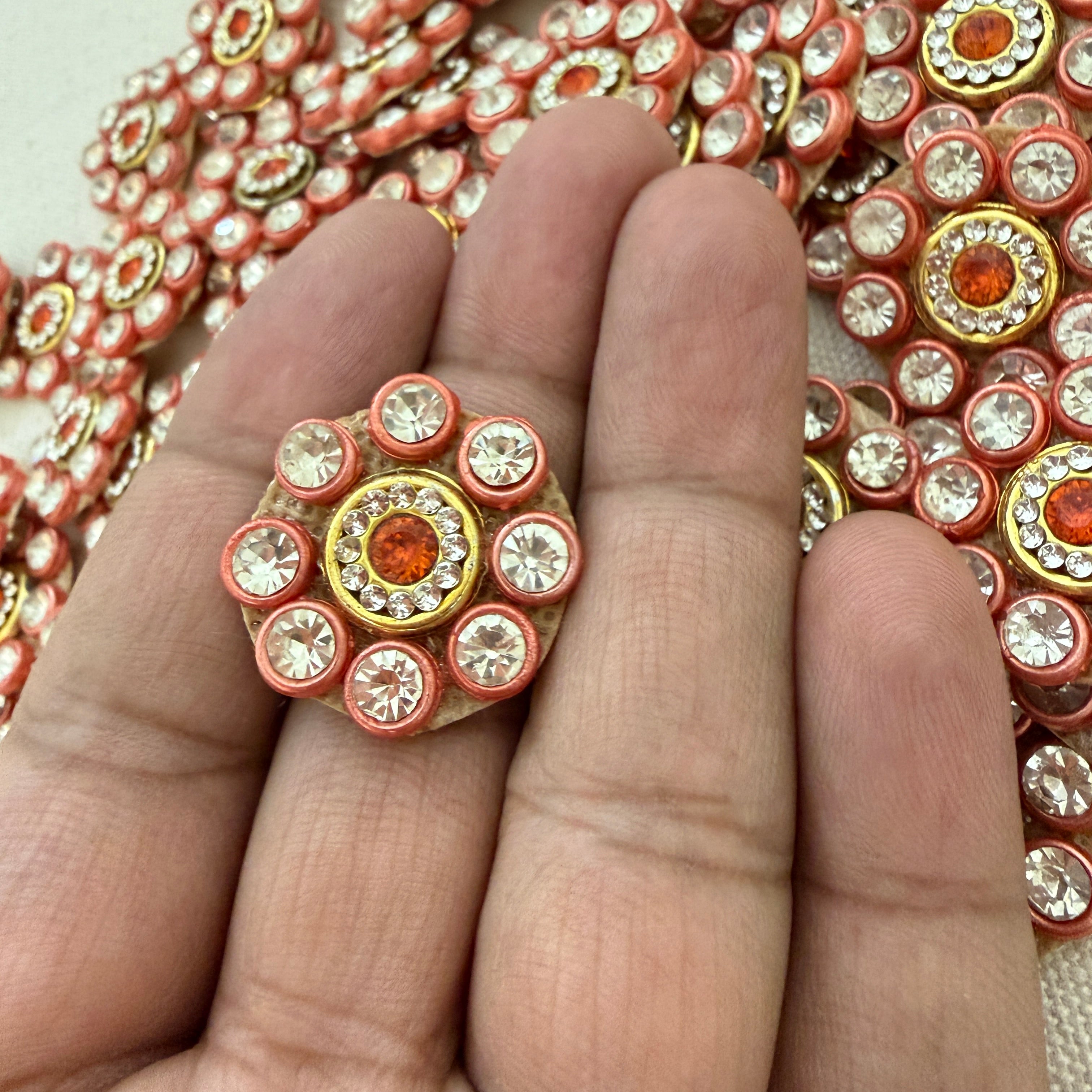 Decorative ring with colorful stones on a hand, with a background of similar jewelry pieces.