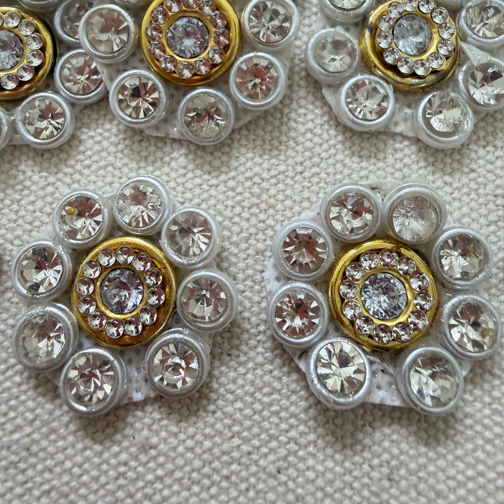 Close-up of decorative buttons with gemstone-like embellishments on a textured surface.