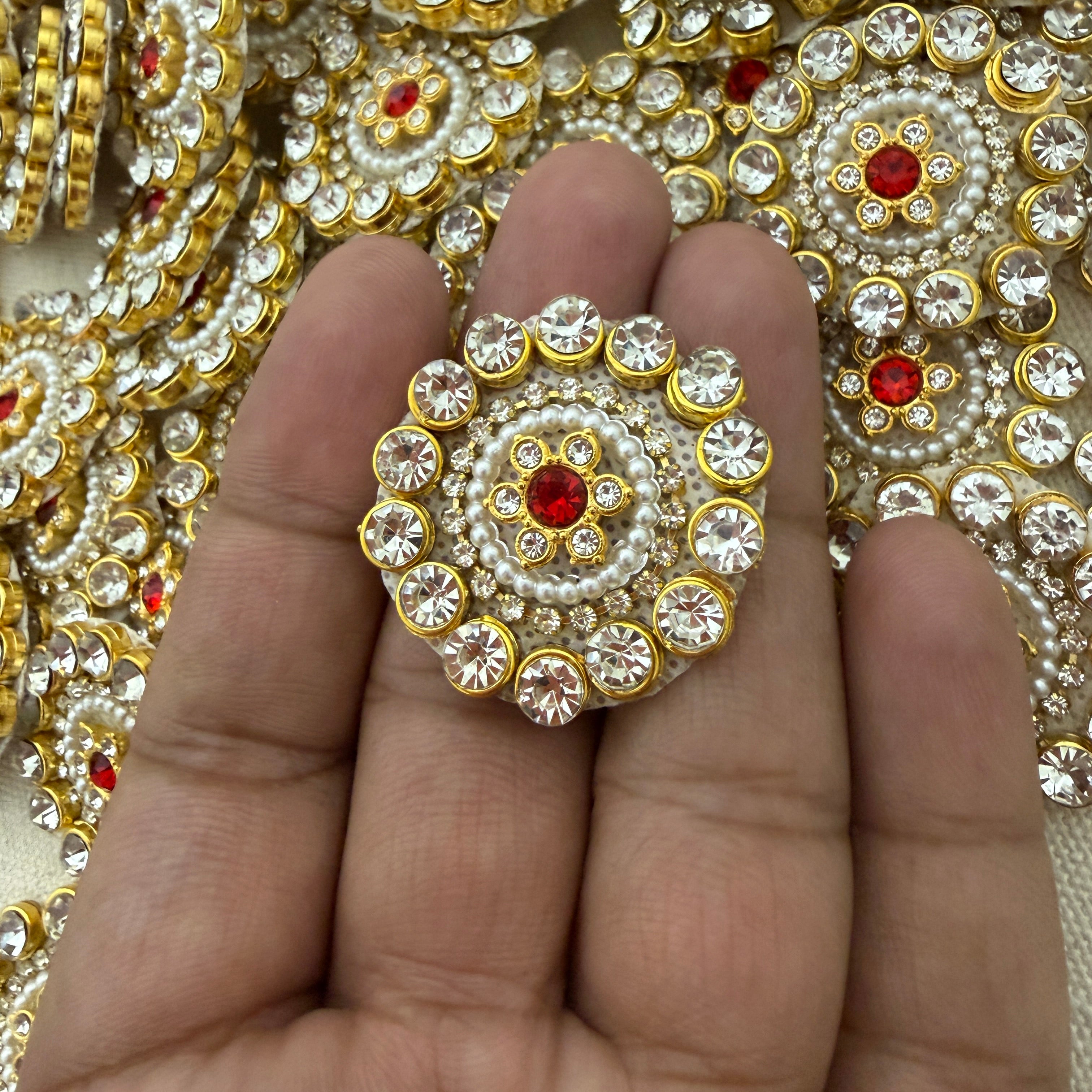Decorative gemstone button held between fingers with a background of similar buttons.