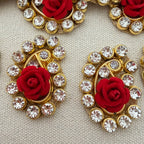 Decorative earrings with red roses and clear crystals on a beige background