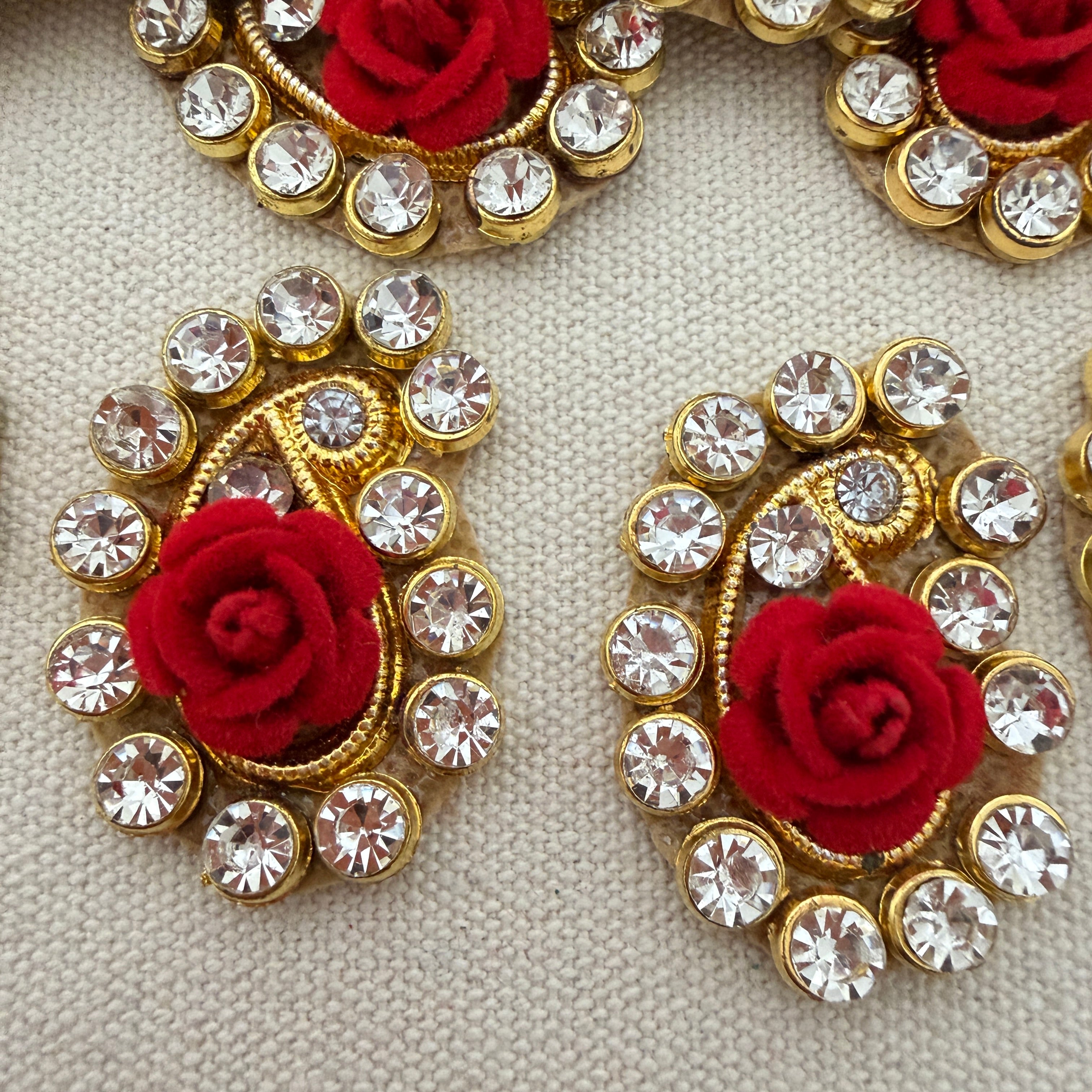 Decorative earrings with red roses and clear crystals on a beige background