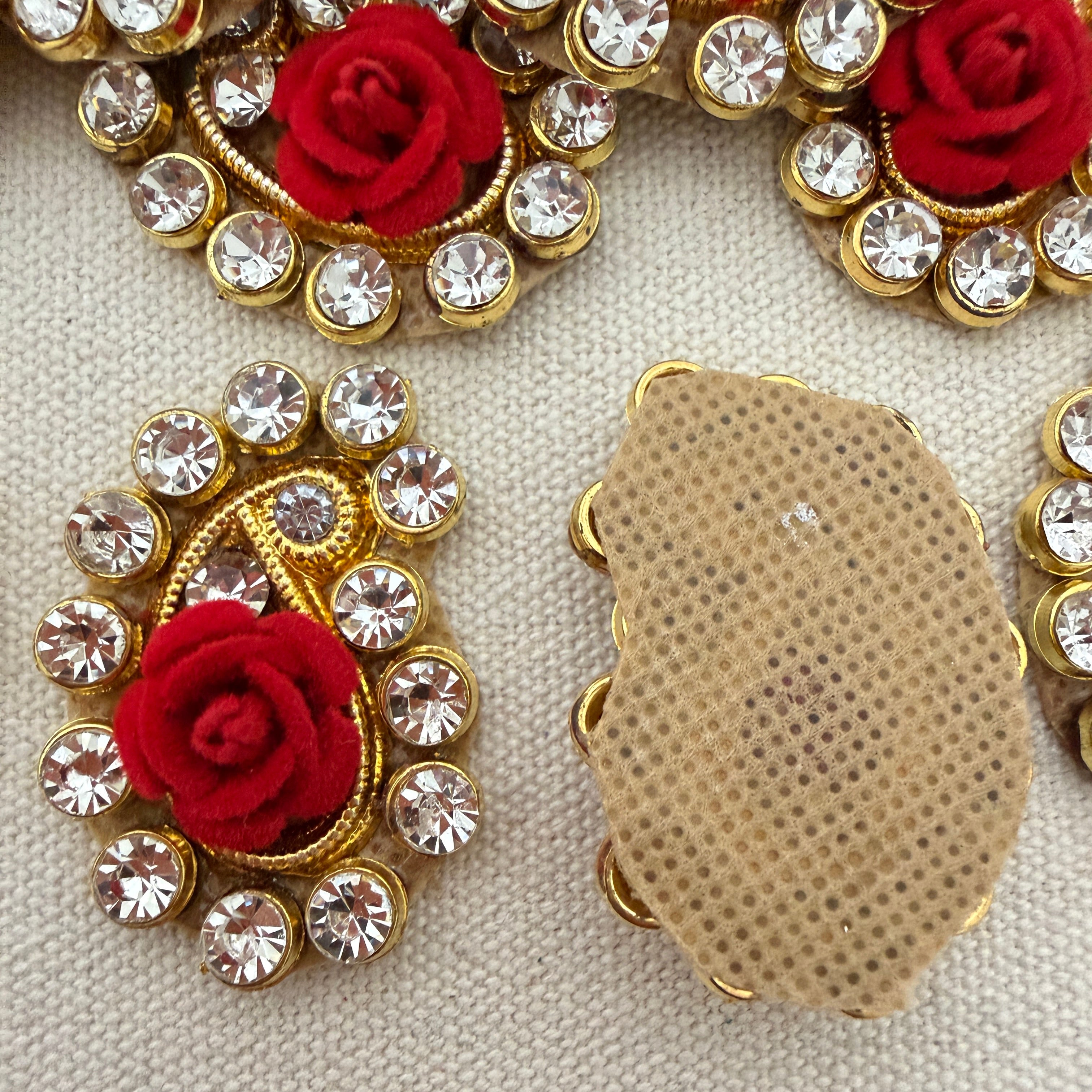 Decorative brooches with red roses and gold and crystal details on a beige background