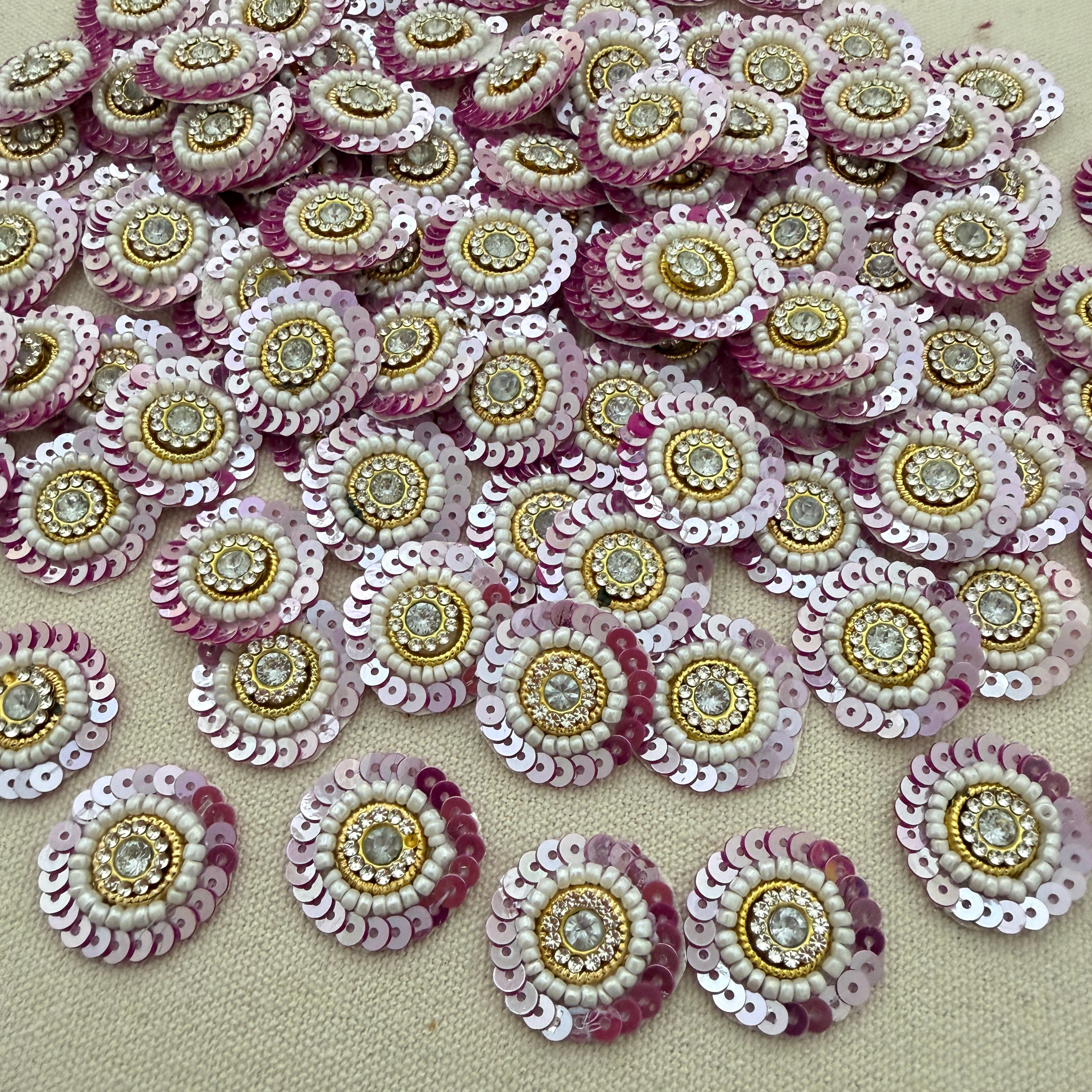 Sequined embellishments with pink, gold, and white colors on a beige background