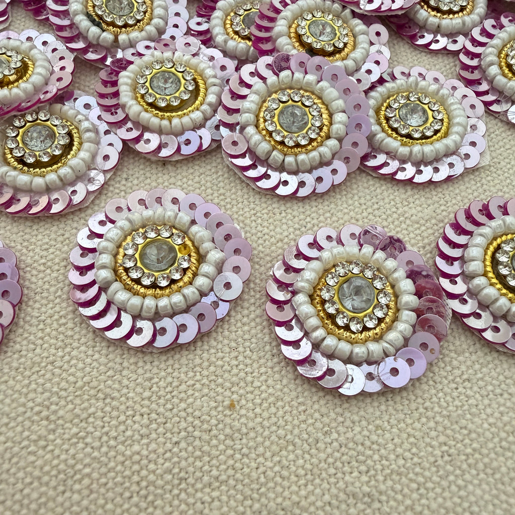 Decorative circular embellishments with sequins and beads on a textured beige surface