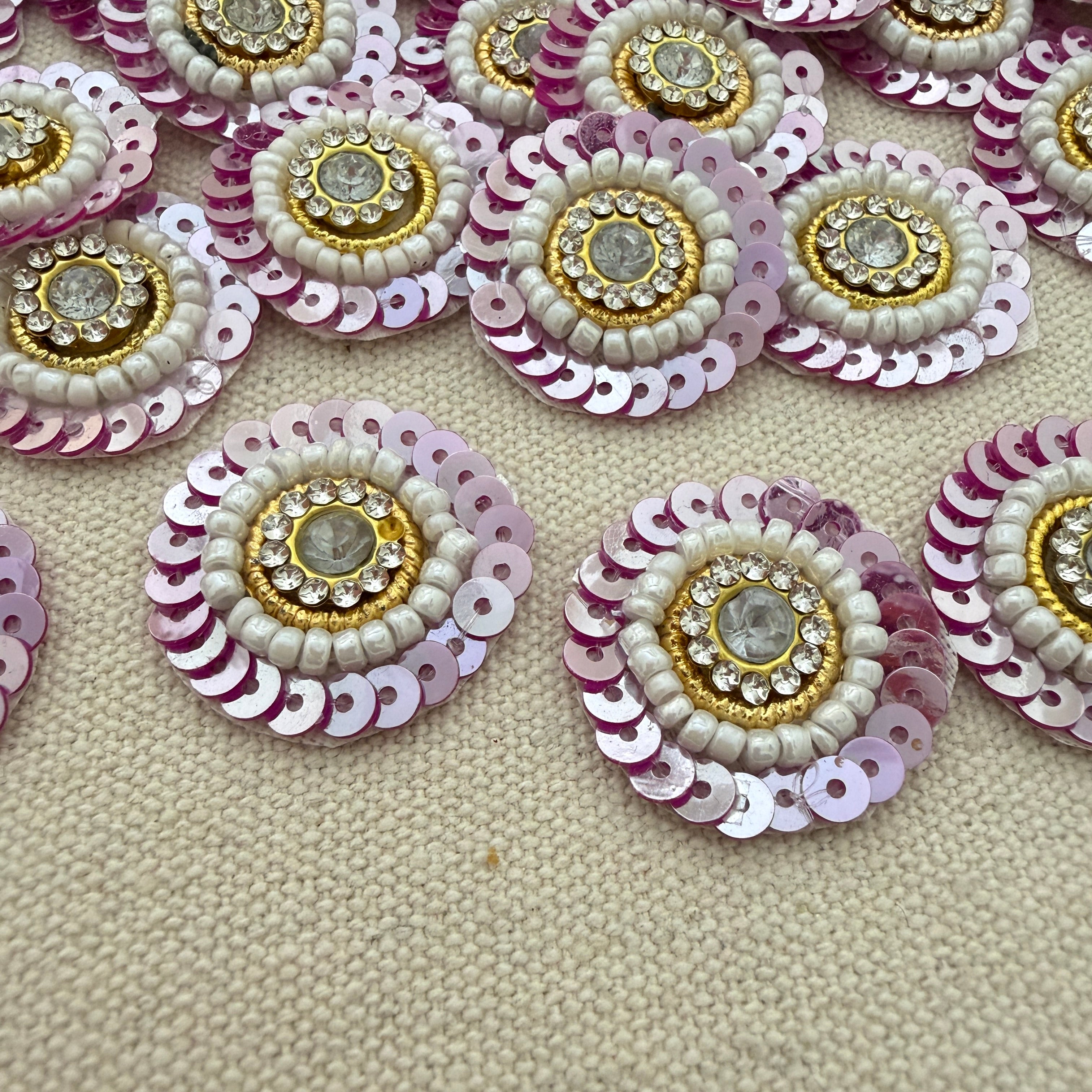 Decorative circular embellishments with sequins and beads on a textured beige surface