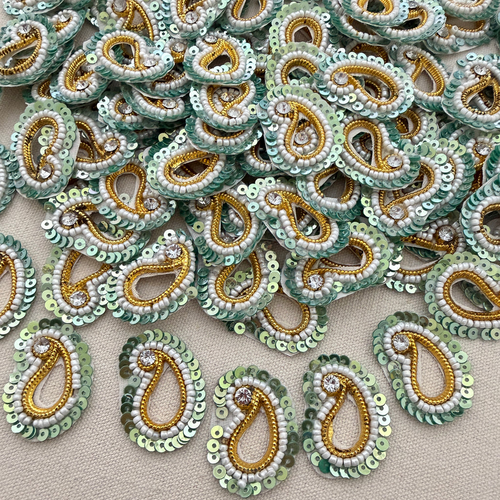 Collection of green and gold beaded paisley designs on a beige background