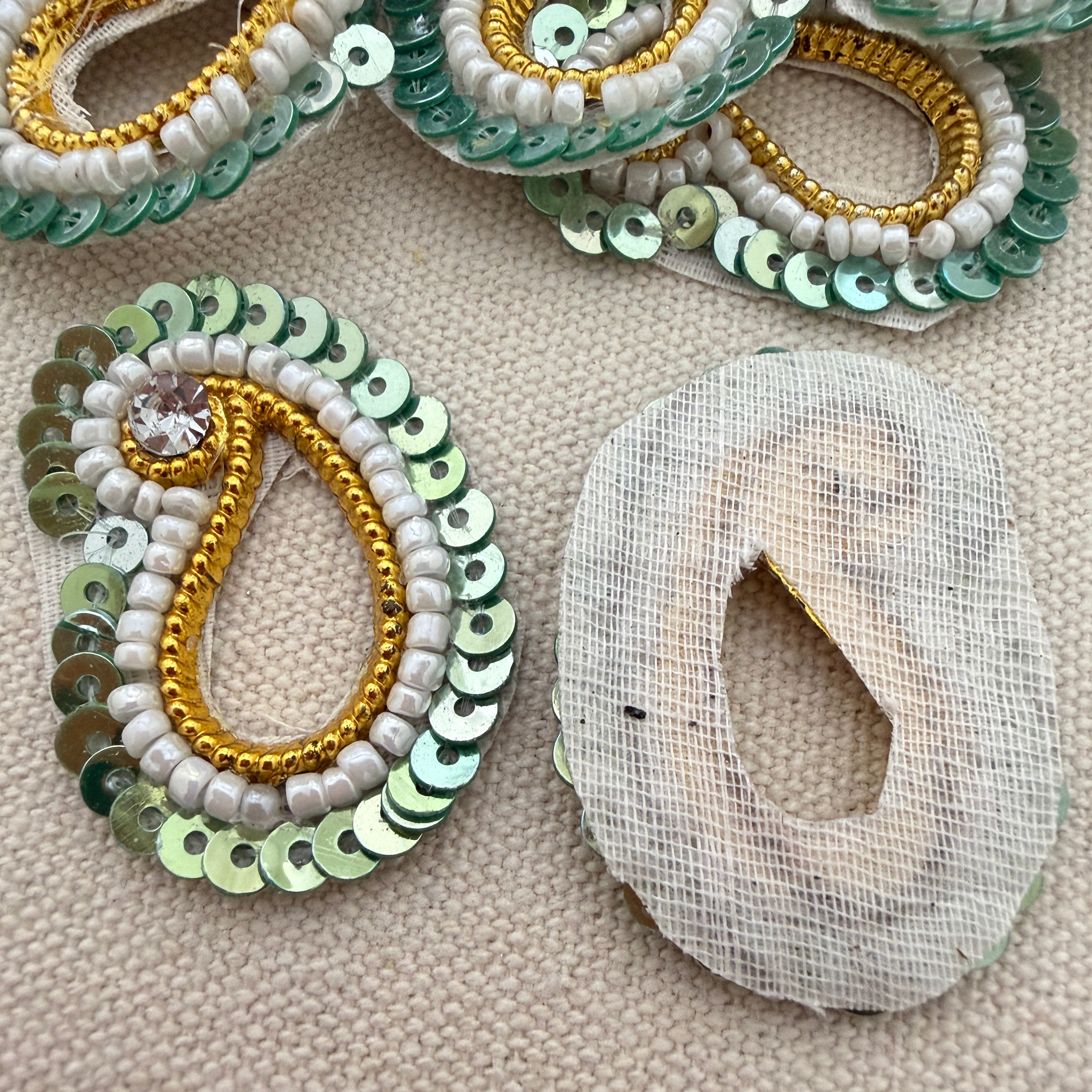 Decorative earrings with sequins and beads on a textured surface