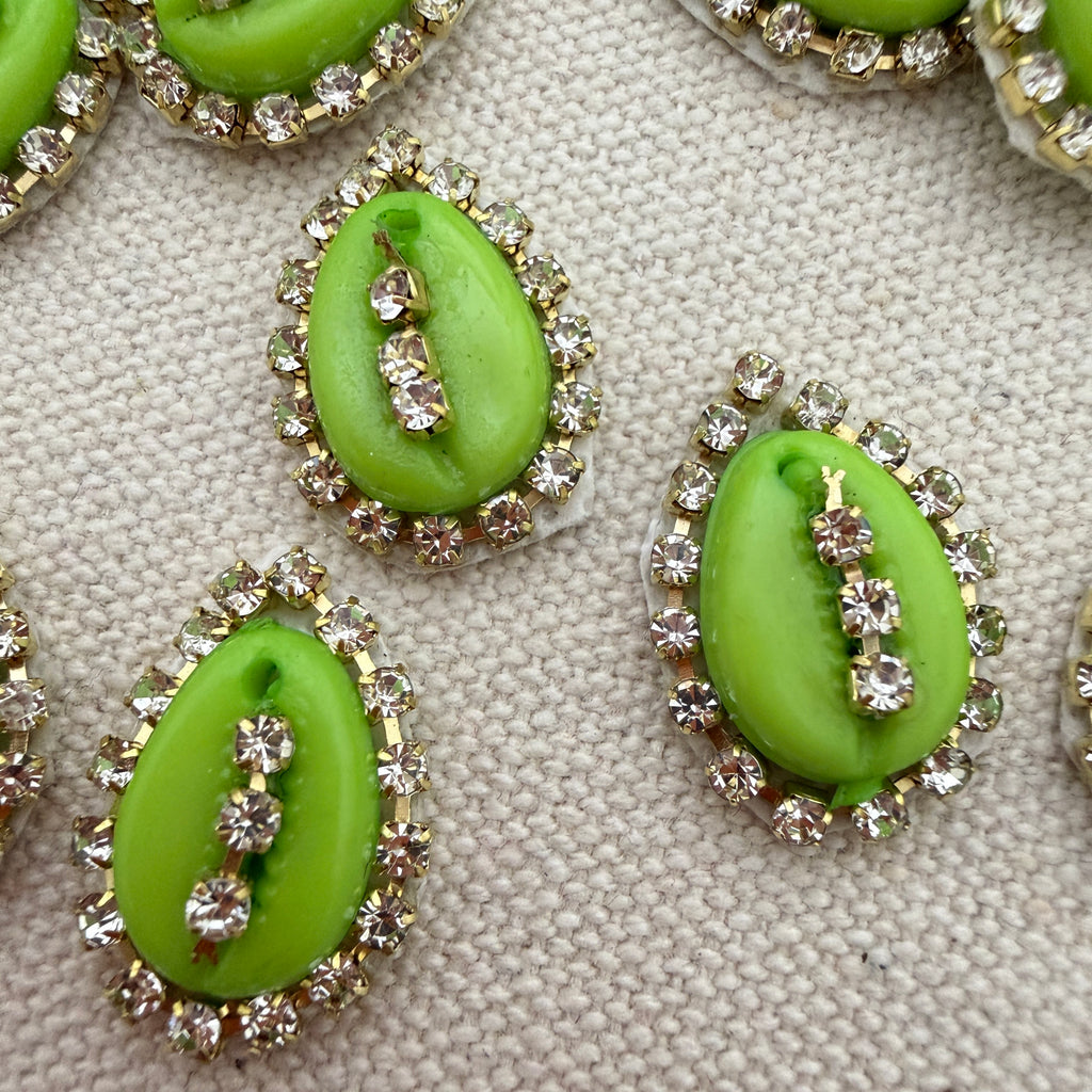 Green kiwi slices with decorative rhinestone rings on a textured surface