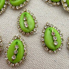 Green kiwi slices with decorative rhinestone rings on a textured surface