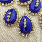 Blue cabochon stones with rhinestone accents on a beige fabric background