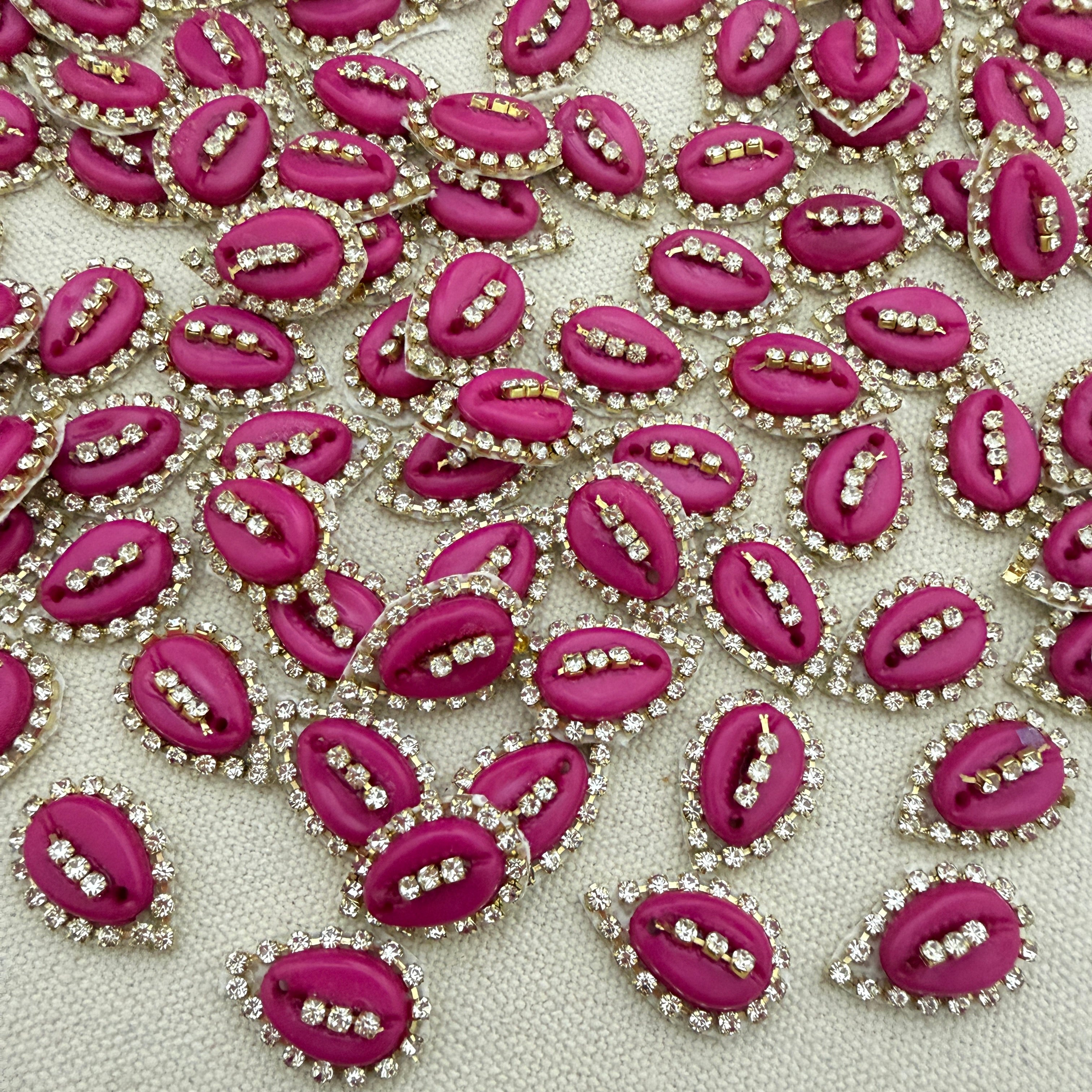 Pink lip-shaped embellishments with rhinestones on a light gray background