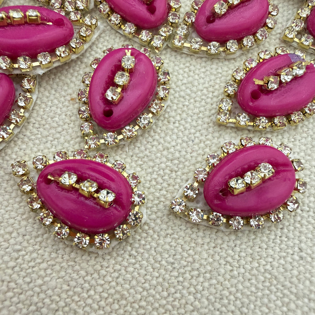 Pink lip-shaped buttons with rhinestone embellishments on a textured beige background