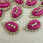 Pink lip-shaped buttons with rhinestone embellishments on a textured beige background