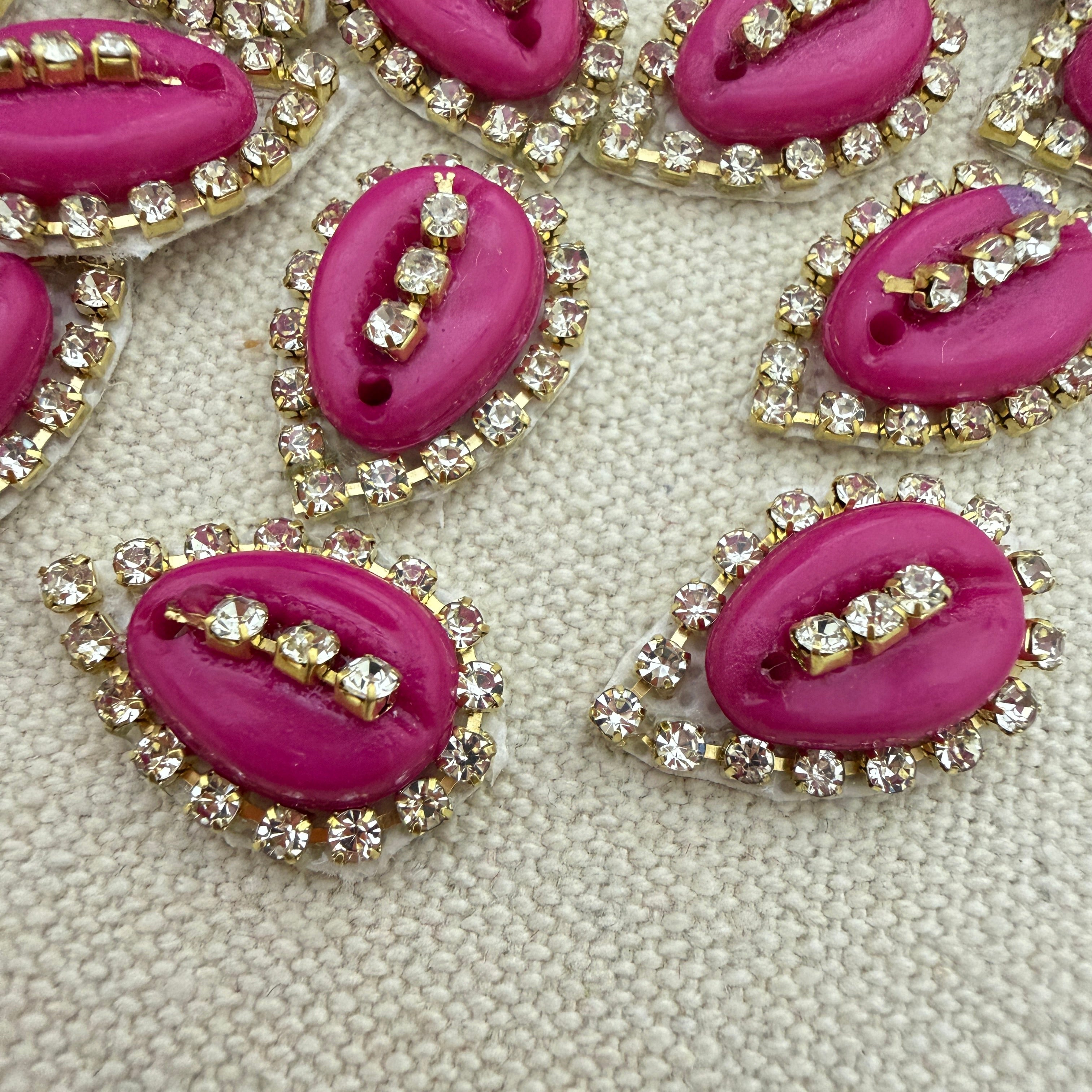 Pink lip-shaped buttons with rhinestone embellishments on a textured beige background