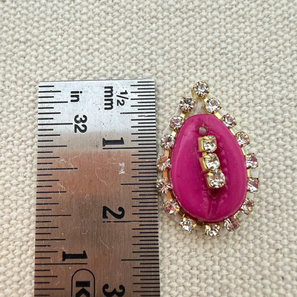 Pink brooch with gemstone measurements against a textured beige background