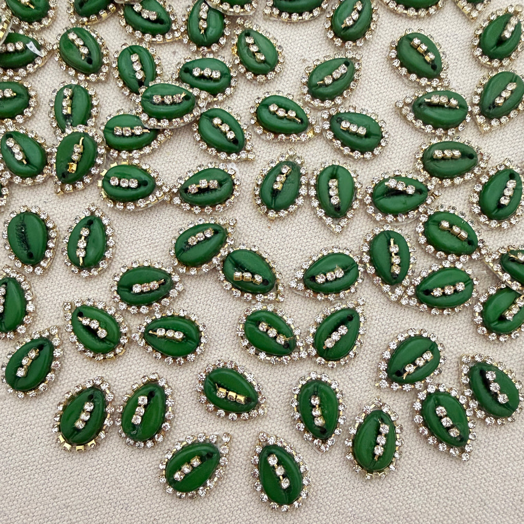 Green leaf-shaped decorative elements with rhinestones on a textured surface