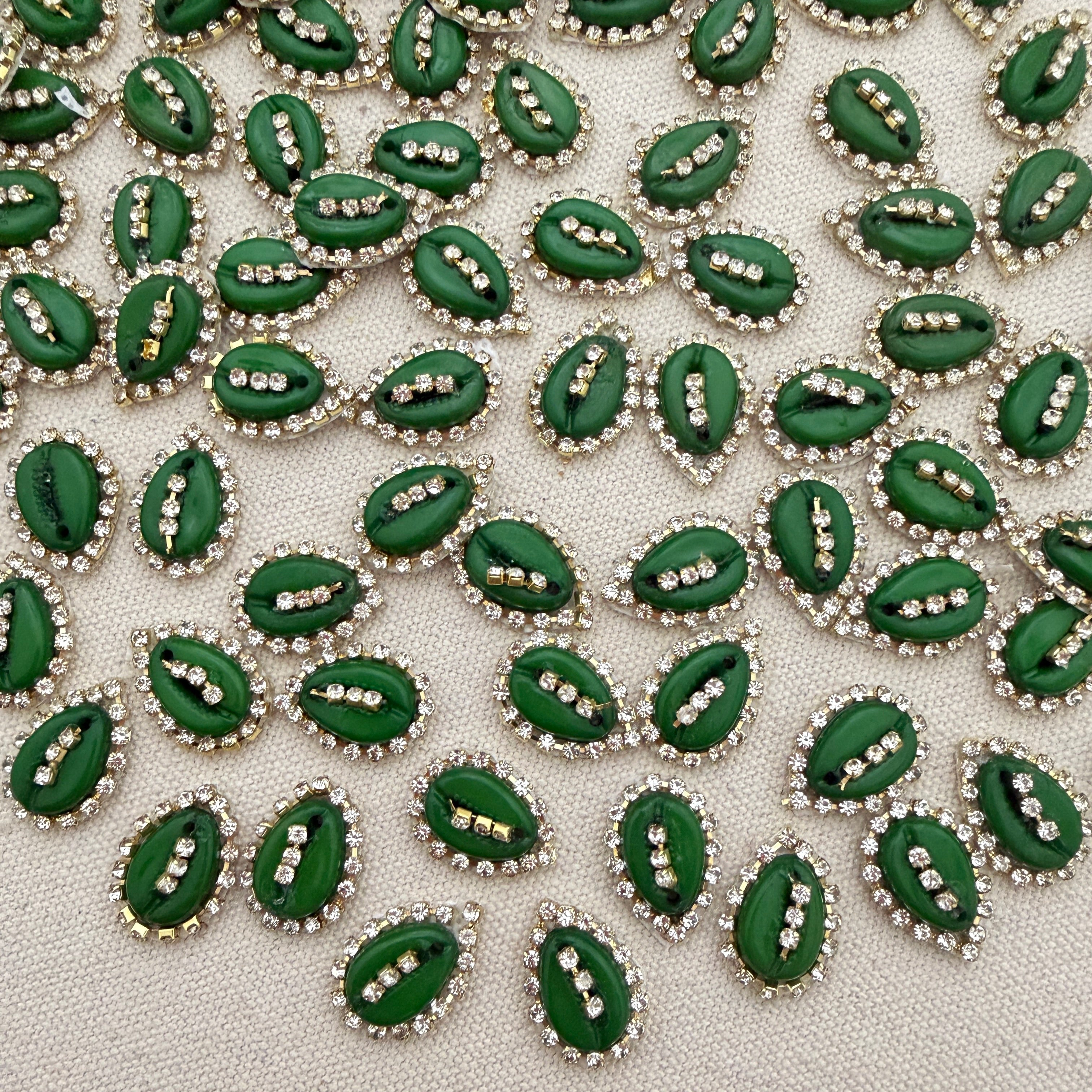 Green leaf-shaped decorative elements with rhinestones on a textured surface