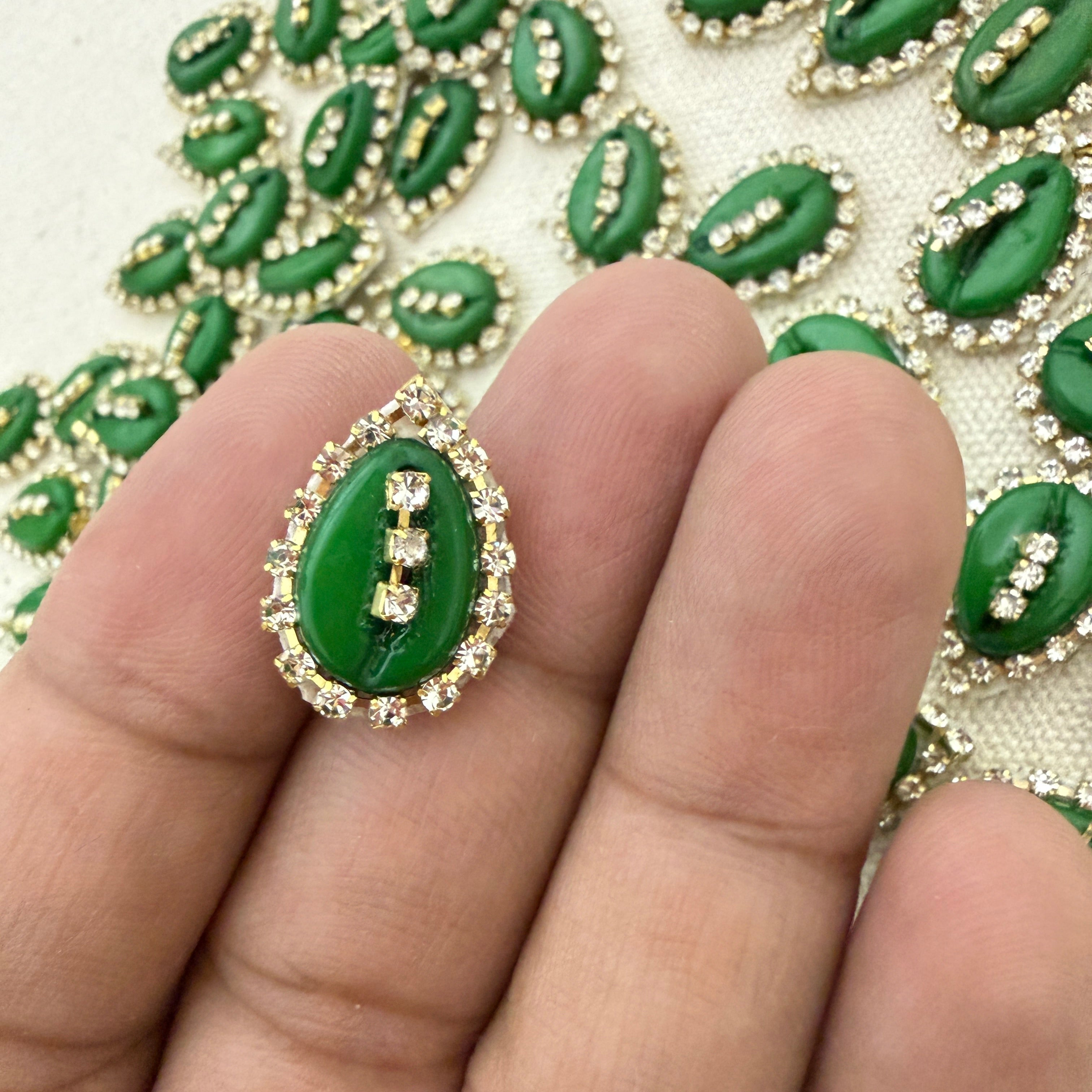 Green leaf-shaped decorative elements with rhinestones on a textured surface