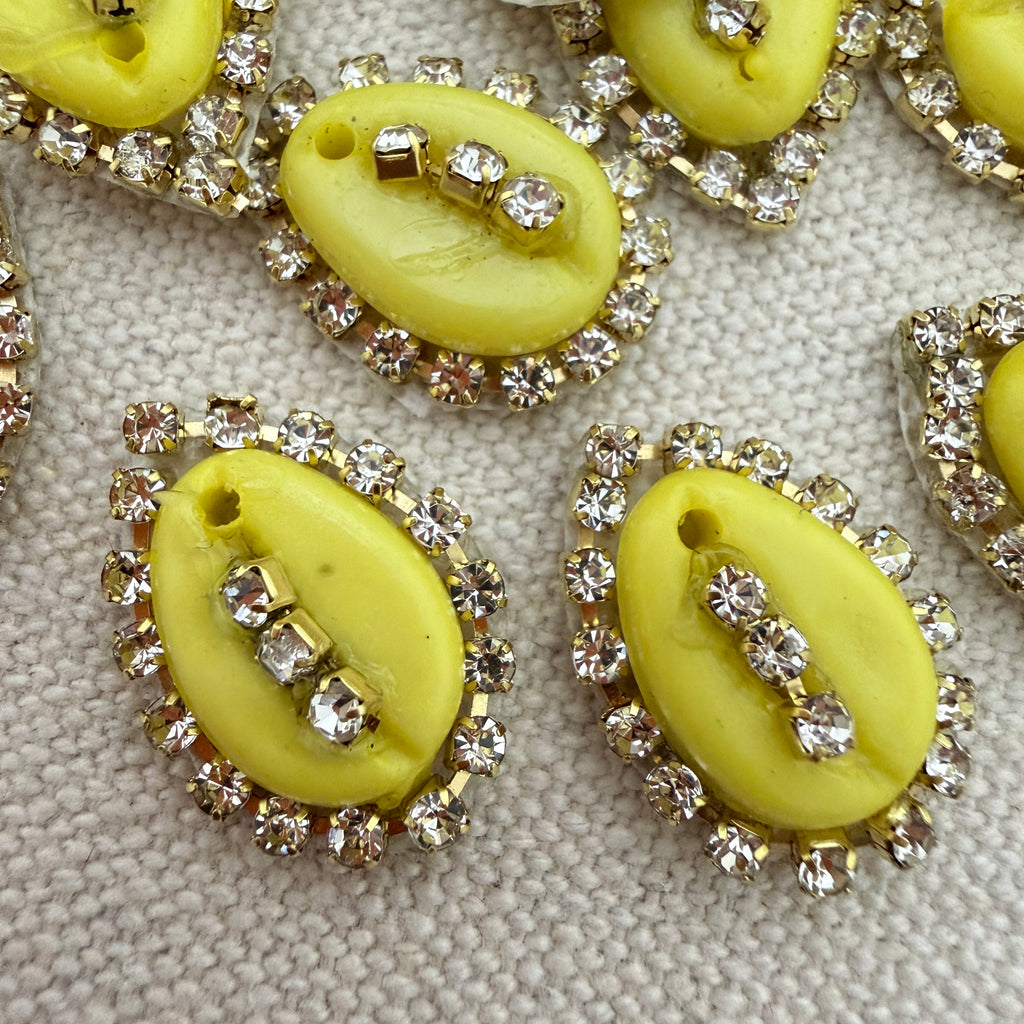 Yellow buttons with rhinestone embellishments on a textured surface