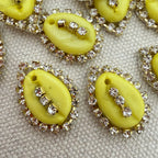Yellow buttons with rhinestone embellishments on a textured surface