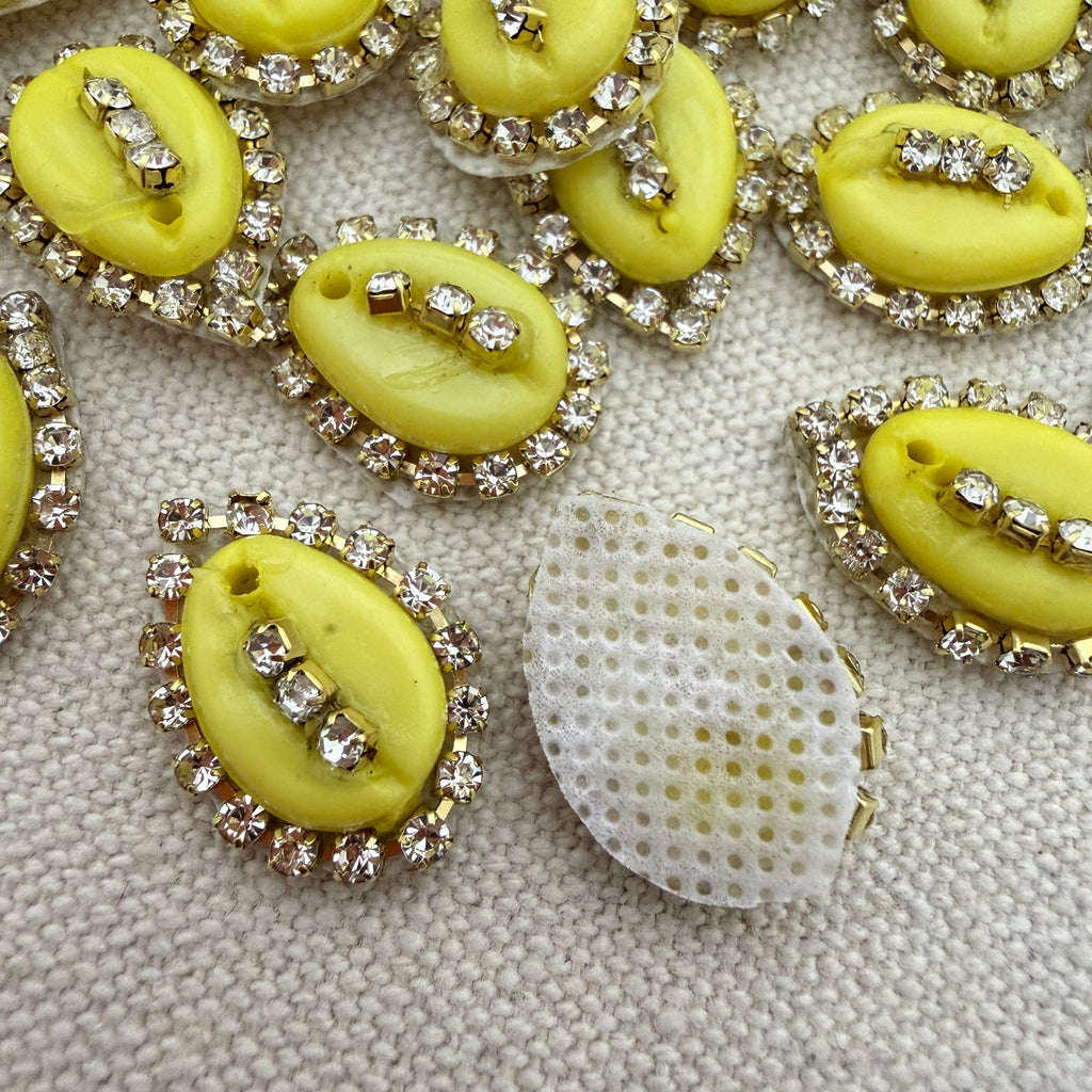 Yellow buttons with rhinestone embellishments on a textured surface