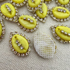 Yellow buttons with rhinestone embellishments on a textured surface