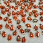 Pattern of red and silver embellishments on a textured white background