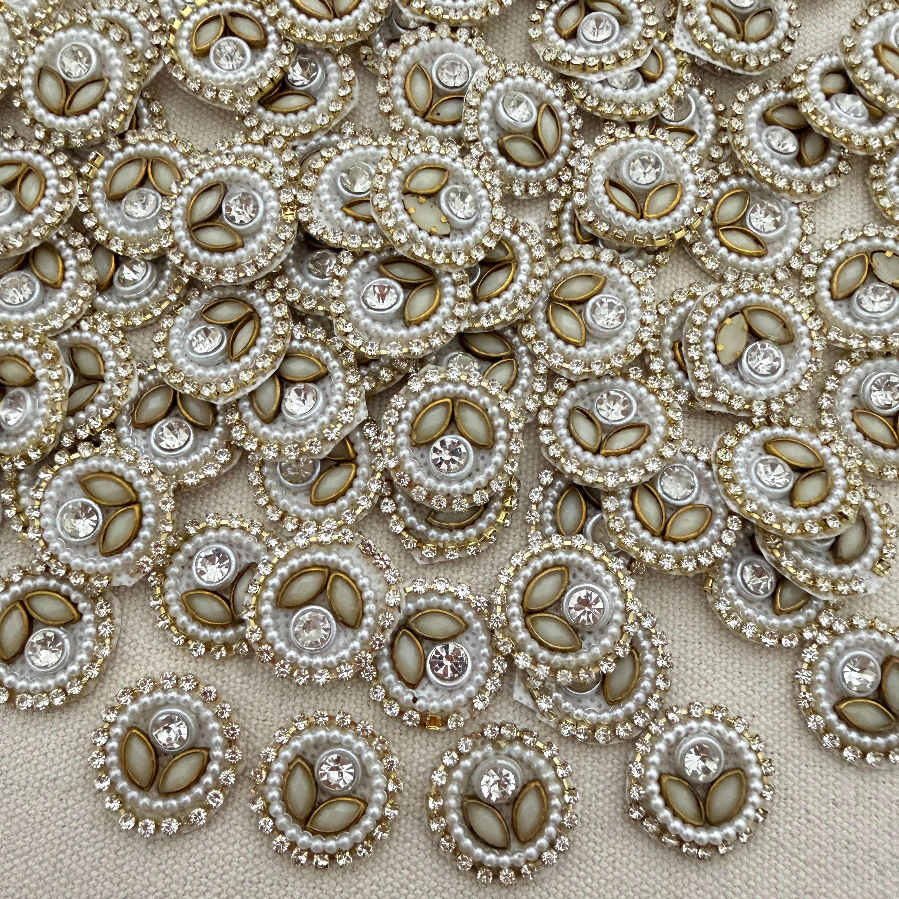 Close-up of decorative buttons with pearls and crystals on a beige fabric background