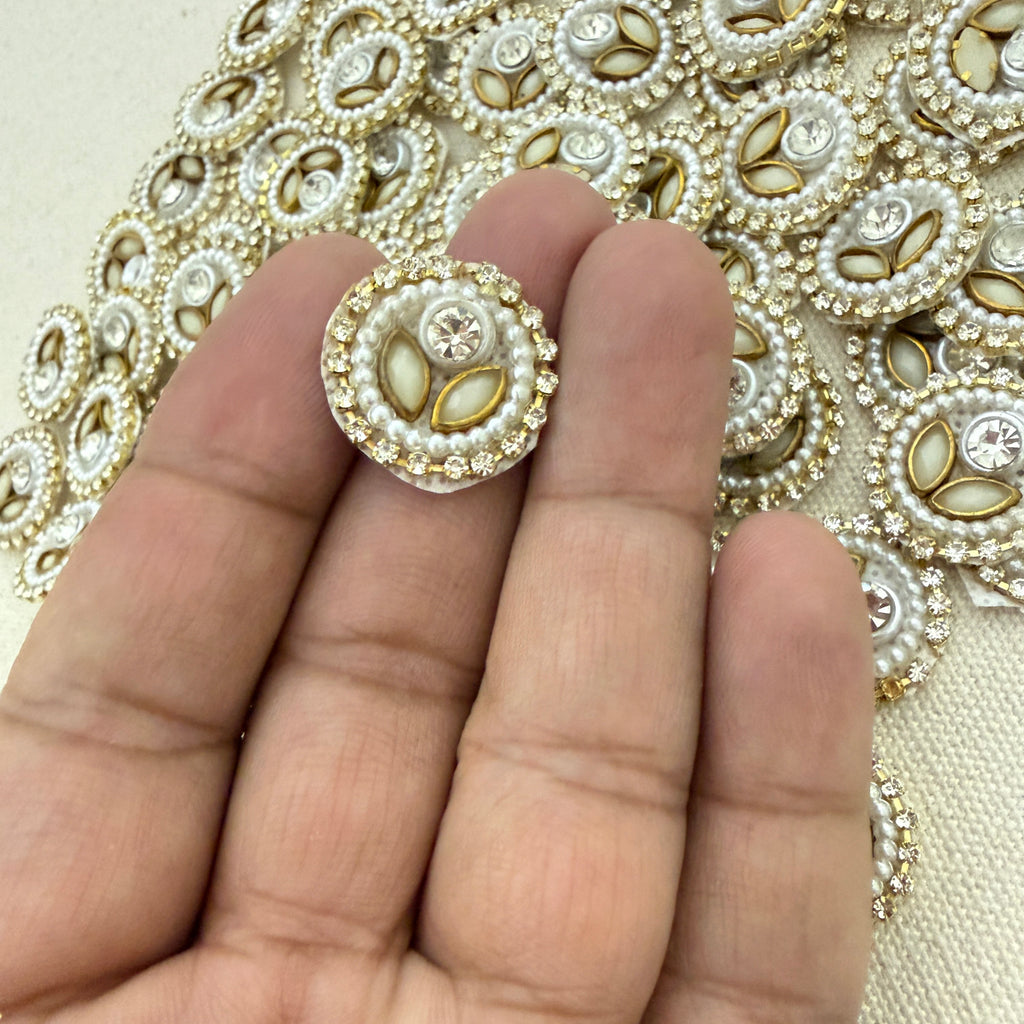 Decorative button held between fingers with embroidered fabric background