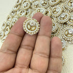 Decorative button held between fingers with embroidered fabric background