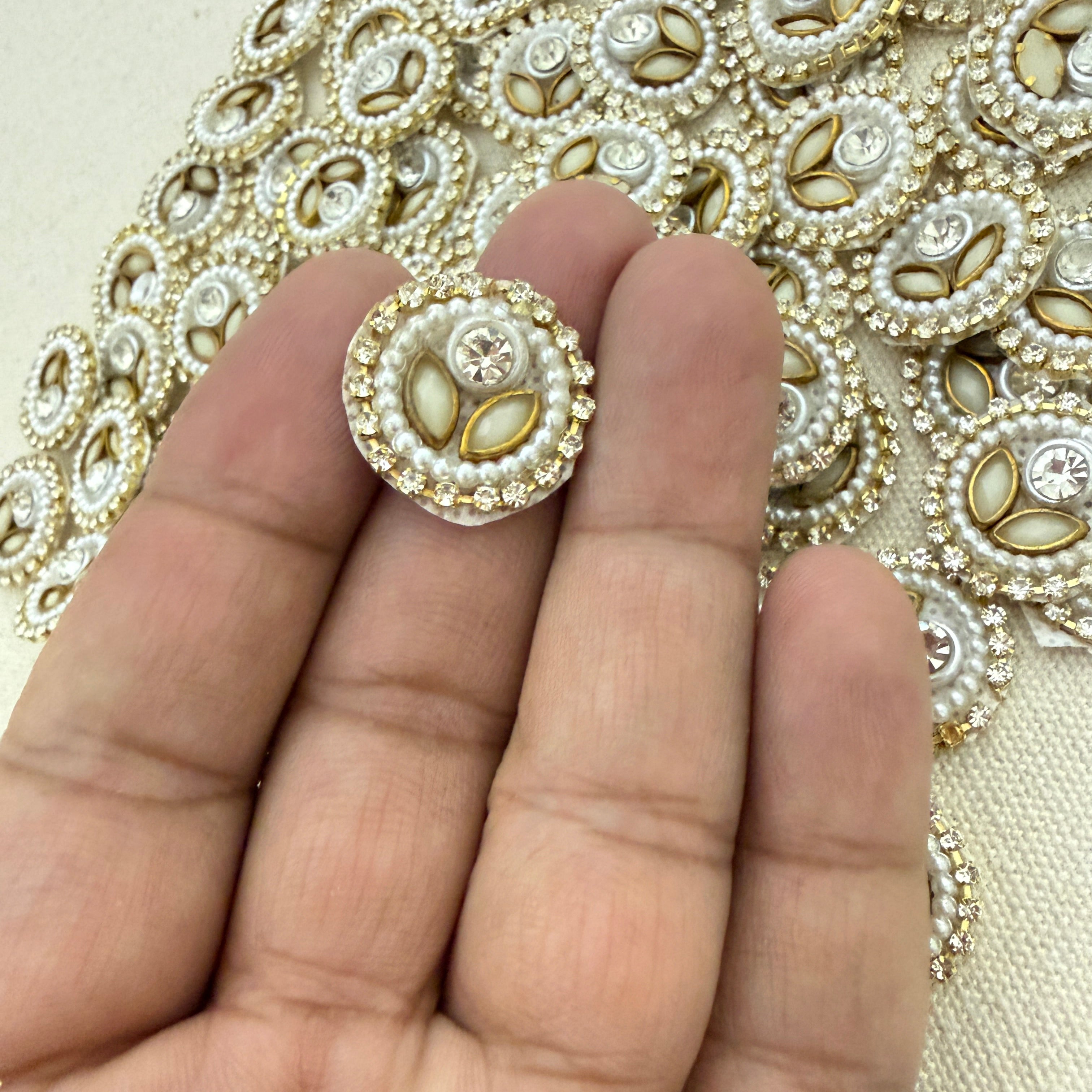 Decorative button held between fingers with embroidered fabric background