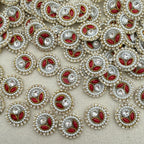 Close-up of decorative buttons with red centers, pearls, and crystals on a beige background