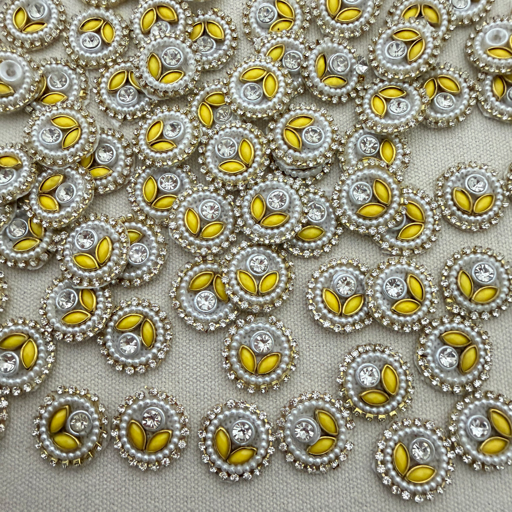 Close-up of decorative buttons with yellow centers and pearl-like borders on a light gray background