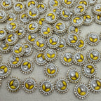 Close-up of decorative buttons with yellow centers and pearl-like borders on a light gray background