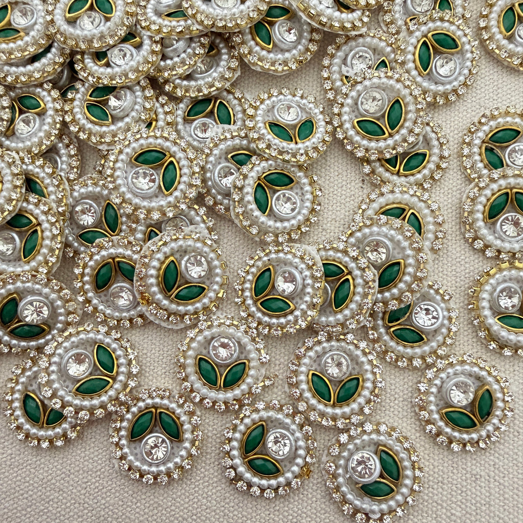 Close-up of decorative elements with pearls, green leaves, and crystals on a beige background