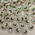 Close-up of decorative elements with pearls, green leaves, and crystals on a beige background