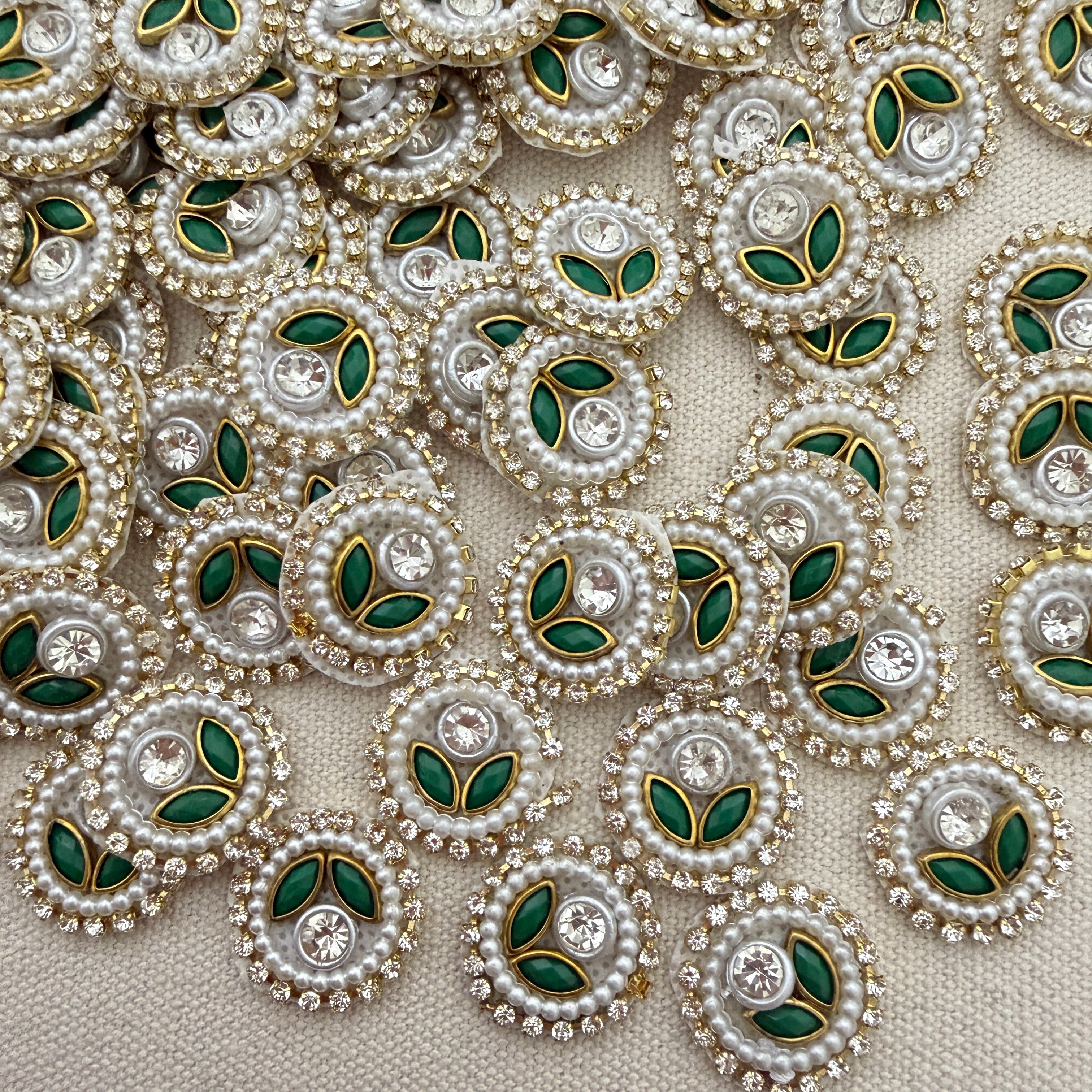 Close-up of decorative elements with pearls, green leaves, and crystals on a beige background