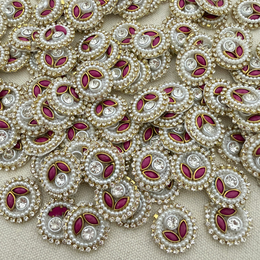Close-up of decorative elements with pearls, red stones, and gold accents on a beige background