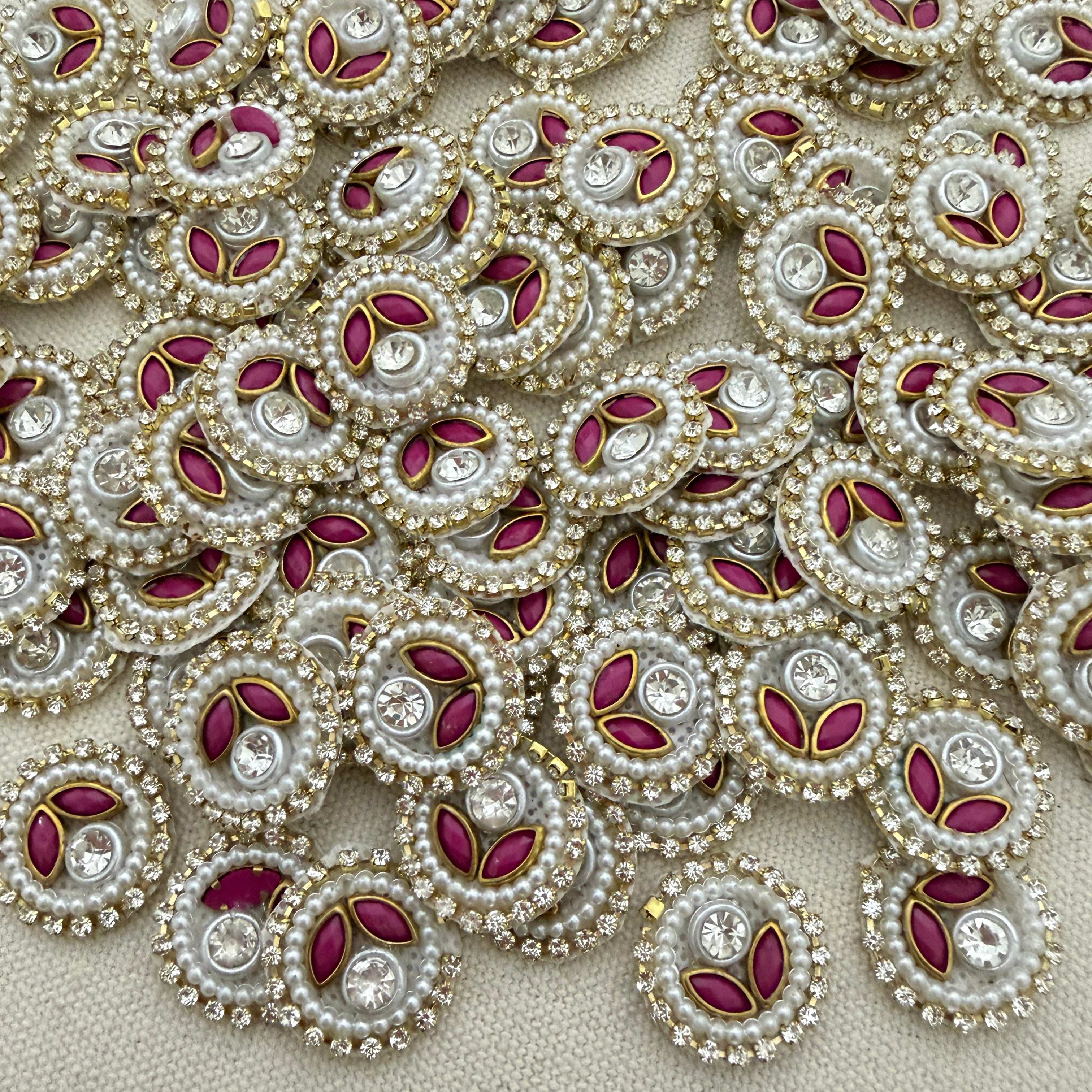 Close-up of decorative elements with pearls, red stones, and gold accents on a beige background